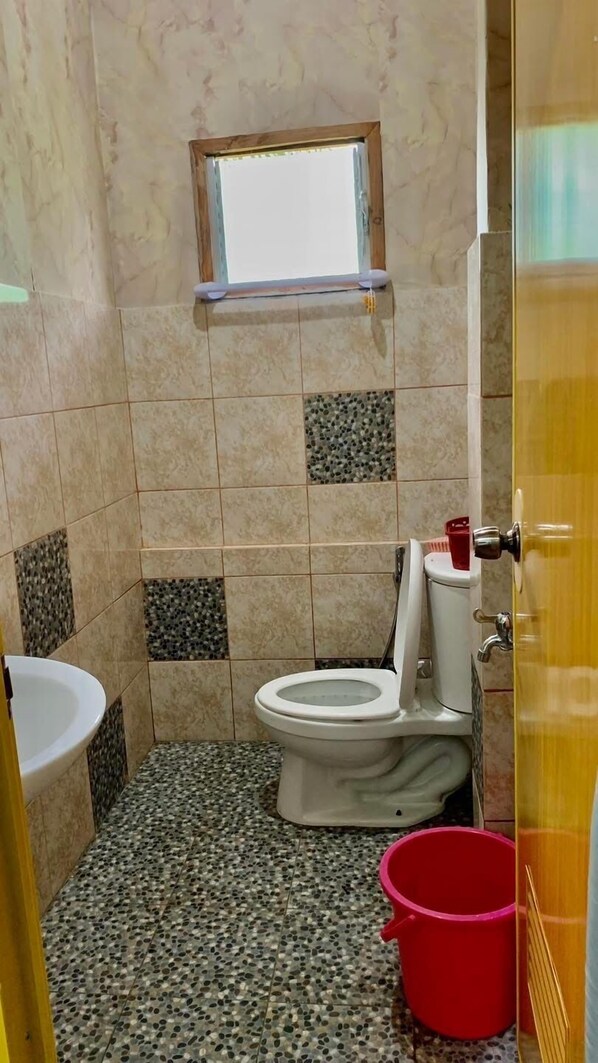 A small bathroom with a toilet, a sink, and a window.