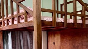 Un lit superposé avec une structure en bois, un lit inférieur doté d’un matelas et d’oreillers, et une tête de lit.