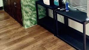 Une pièce dotée d’un téléviseur fixé au mur, d’une petite table avec une bouilloire et une machine à café, d’un meuble avec un plan de travail en marbre et d’un plancher en bois.