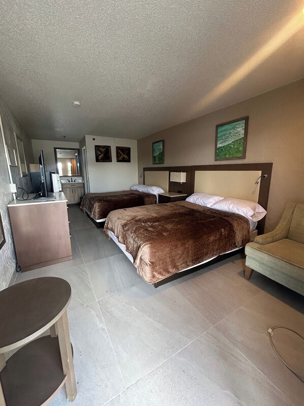 Une chambre d’hôtel avec deux lits, un bureau, une chaise et une petite table.