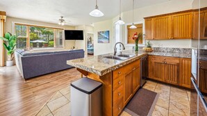 A modern kitchen with granite countertops, wooden cabinets, and a central island.