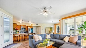 A modern living room with a sectional sofa, a glass coffee table, and a ceiling fan.