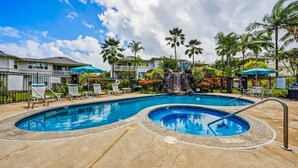 A swimming pool with lounge chairs and palm trees.