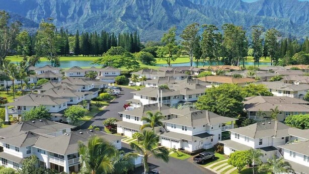 A residential area with houses, a golf course, and mountains in the background.