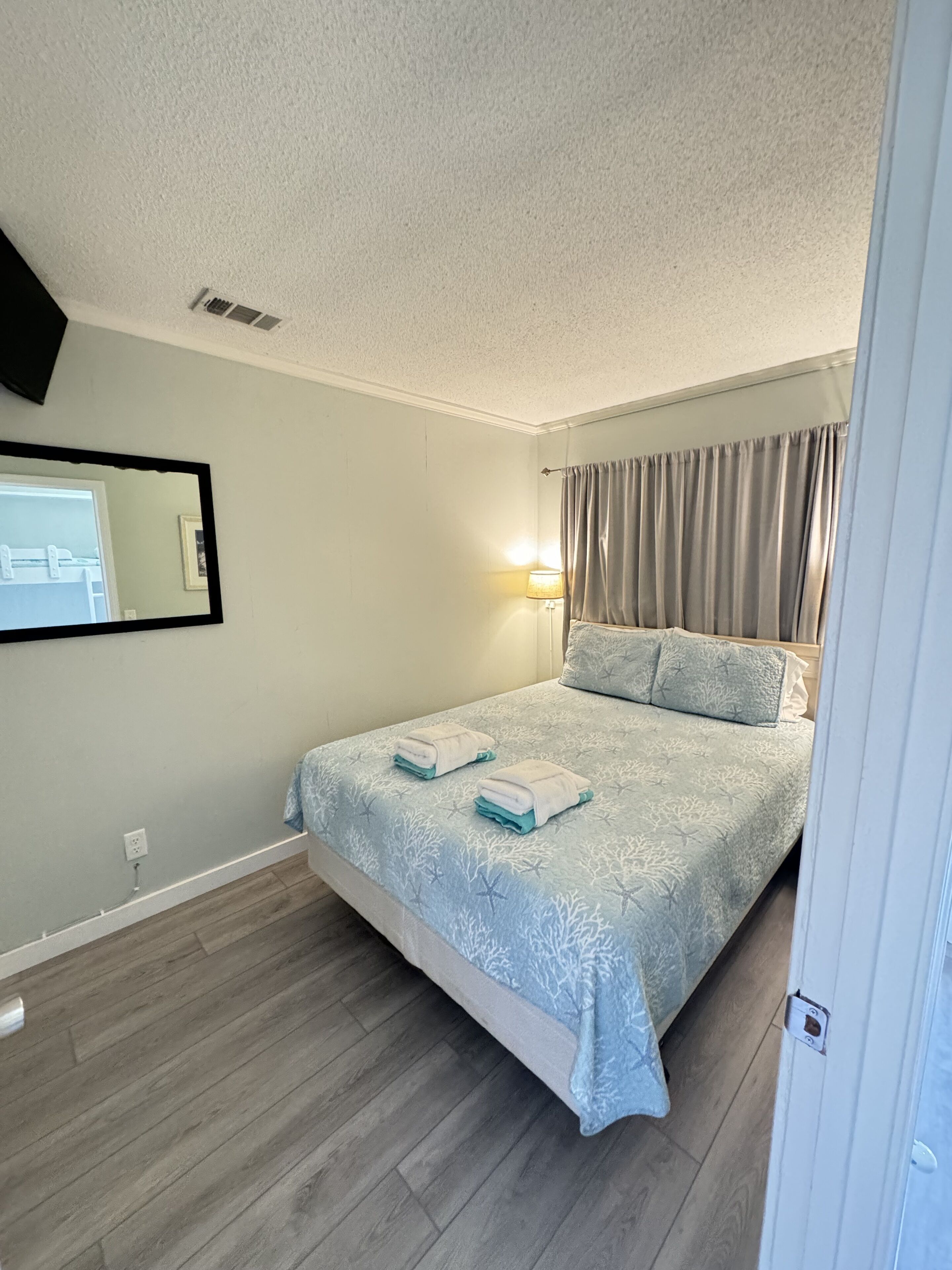 Une chambre à coucher avec un lit, une table de chevet, une lampe et un miroir.