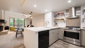 Una cocina moderna con lavavajillas, horno y un comedor con una silla amarilla.