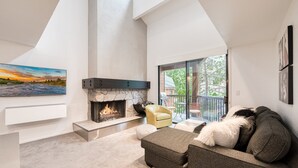 Una sala de estar moderna con chimenea de piedra, un sofá y una butaca.
