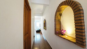 A hallway with a wooden door, a brick archway, and a potted plant.