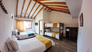 A dormitory room with bunk beds, a wardrobe, and a bed with a blue and white quilt.