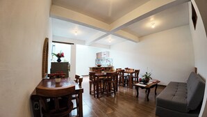 A spacious living area with a dining table and chairs, a sofa, and a kitchen in the background.