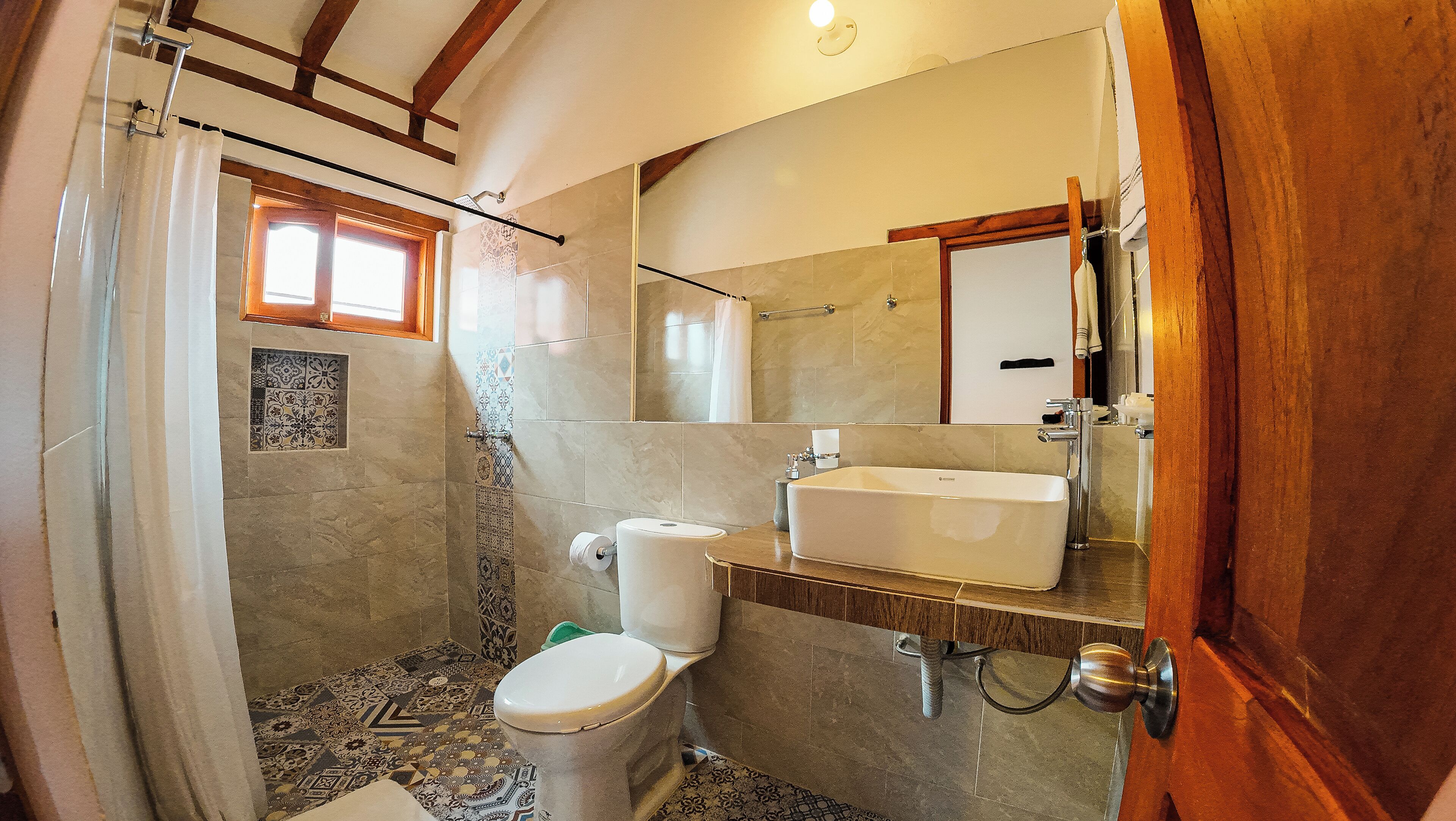 A bathroom with a shower, toilet, sink, and a mirror.