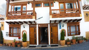 A two-story building with wooden balconies, large windows, and potted plants.