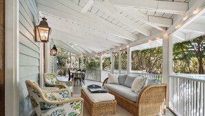 Une véranda couverte, aménagée avec des meubles en osier, une table et des chaises.