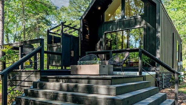 A modern cabin with a large glass window, surrounded by a forest. - Private Lakeside Couples Cabin, Hot Tub & Fire Pit (Bullard)