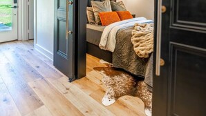 A bedroom with a bed, pillows, and a blanket. There is a door leading to another room. - Private Lakeside Couples Cabin, Hot Tub & Fire Pit (Bullard)