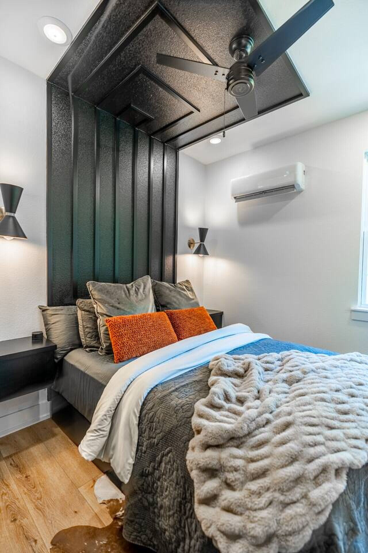 Een moderne slaapkamer met een bed, een plafondventilator en een airconditioning.