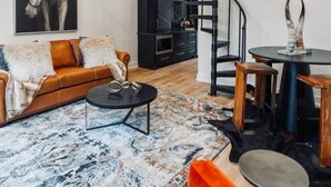 A modern living room with a sofa, coffee table, and a spiral staircase. - Private Lakeside Couples Cabin, Hot Tub & Fire Pit (Bullard)