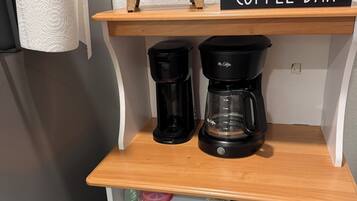 Een keukenhoek met een koffiebar, twee koffiezetapparaten, een bordje met de tekst 'geniet van de kleine dingen' en een bordje met de tekst 'COFFEE BAR'.
