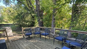 Terraza de madera con sillas azules acolchadas y baranda de madera.