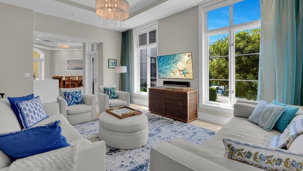 Una sala de estar moderna con un televisor grande, sofás blancos y un mueble de entretenimiento de madera.