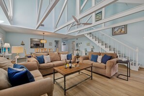 A spacious living room with high ceilings, a staircase, and a modern kitchen in the background. - 536 Queen's Grant @ Palmetto Dunes | Pet-Friendly | Private Patio | Walk to Beach (Hilton Head Island)