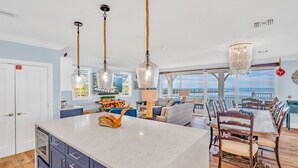 A spacious kitchen with a large island, pendant lights, and a view to the outside. - Emerald Shores – Luxury Oceanfront Rental, Heated Pool & Private Dock. Pets Welcome! (Marathon)