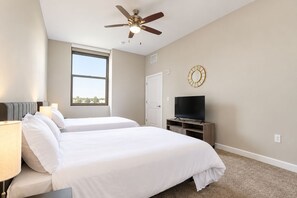 A hotel room with two beds, a ceiling fan, a television on a stand, a window, and a door. - Spacious Dwntwn Suite! RnR HoF, Casino, Stadium (Cleveland)