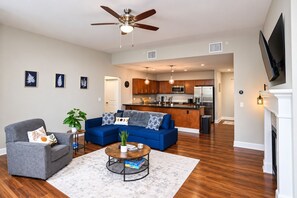 Un salon moderne comprenant un canapé, un fauteuil, une table basse et un ventilateur de plafond.