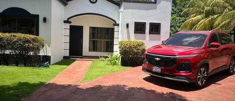 A modern house with a red Chevrolet SUV parked in the driveway.