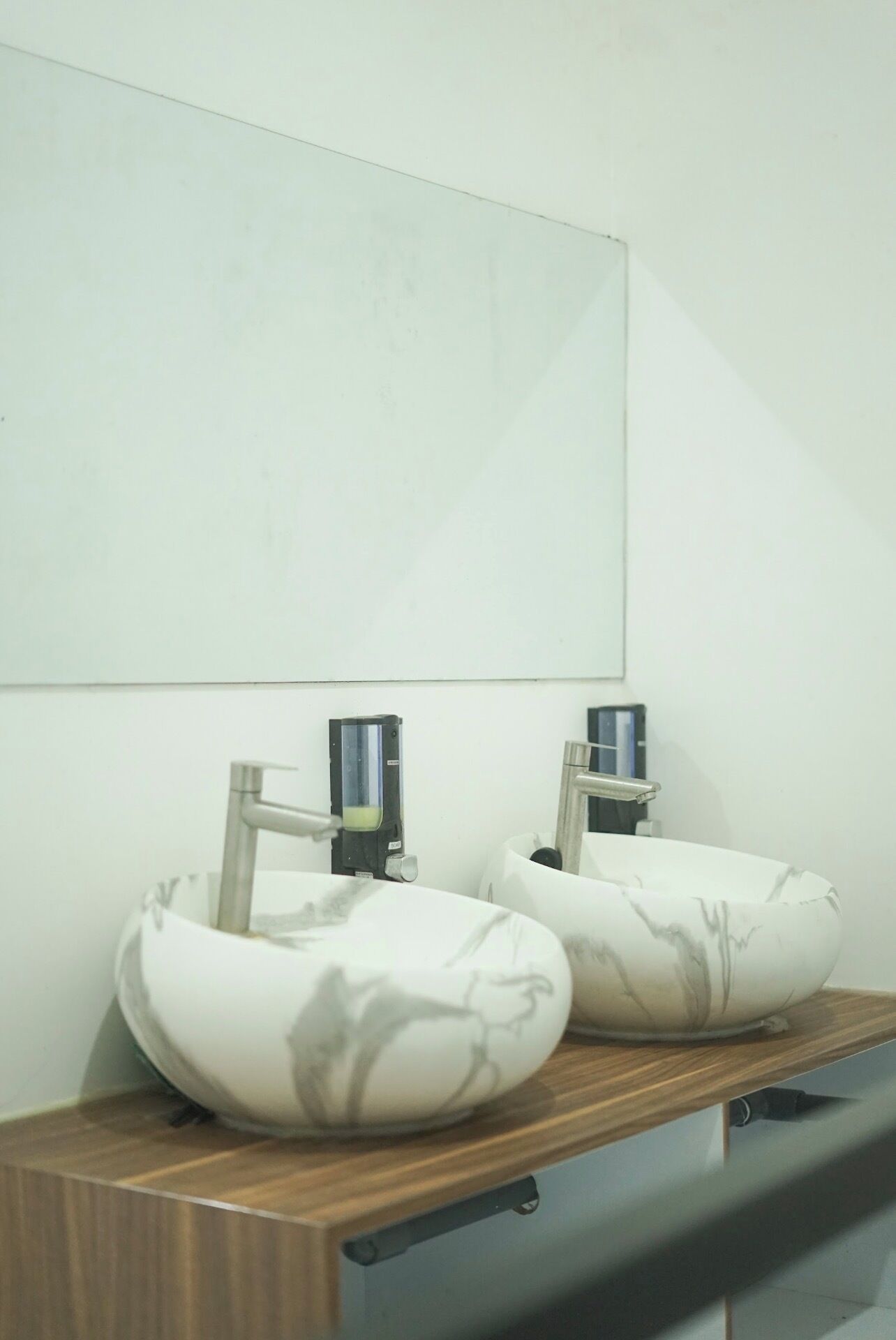 Baño con dos lavamanos sobre encimera de madera y un espejo encima.