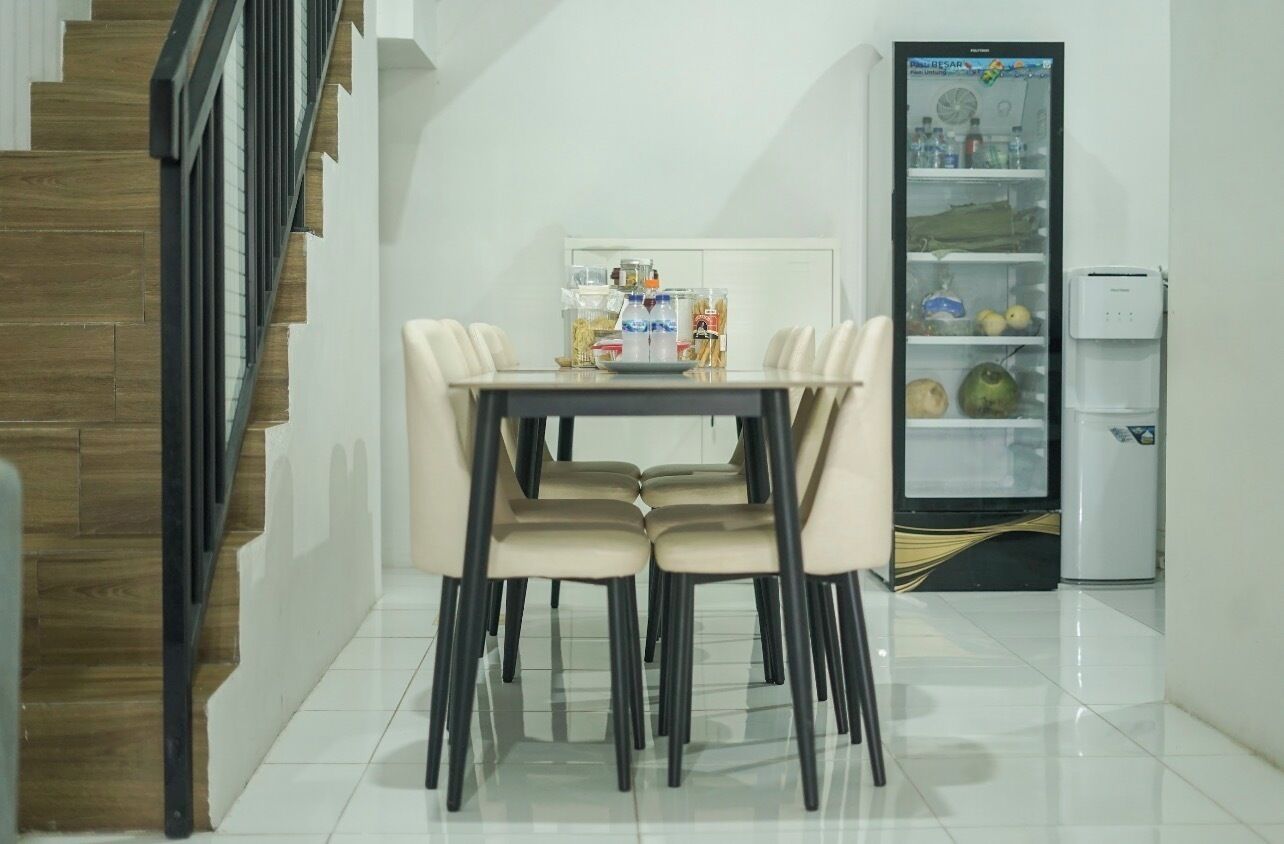 Comedor con mesa, sillas, refrigerador y dispensador de agua.