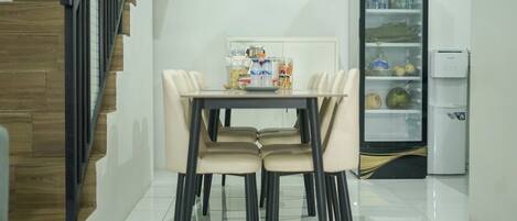 Comedor con mesa, sillas, refrigerador y dispensador de agua.