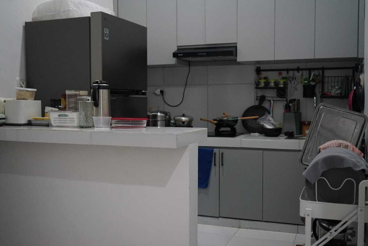 Una cocina con armarios blancos, un refrigerador negro, una estufa y diversos utensilios de cocina.