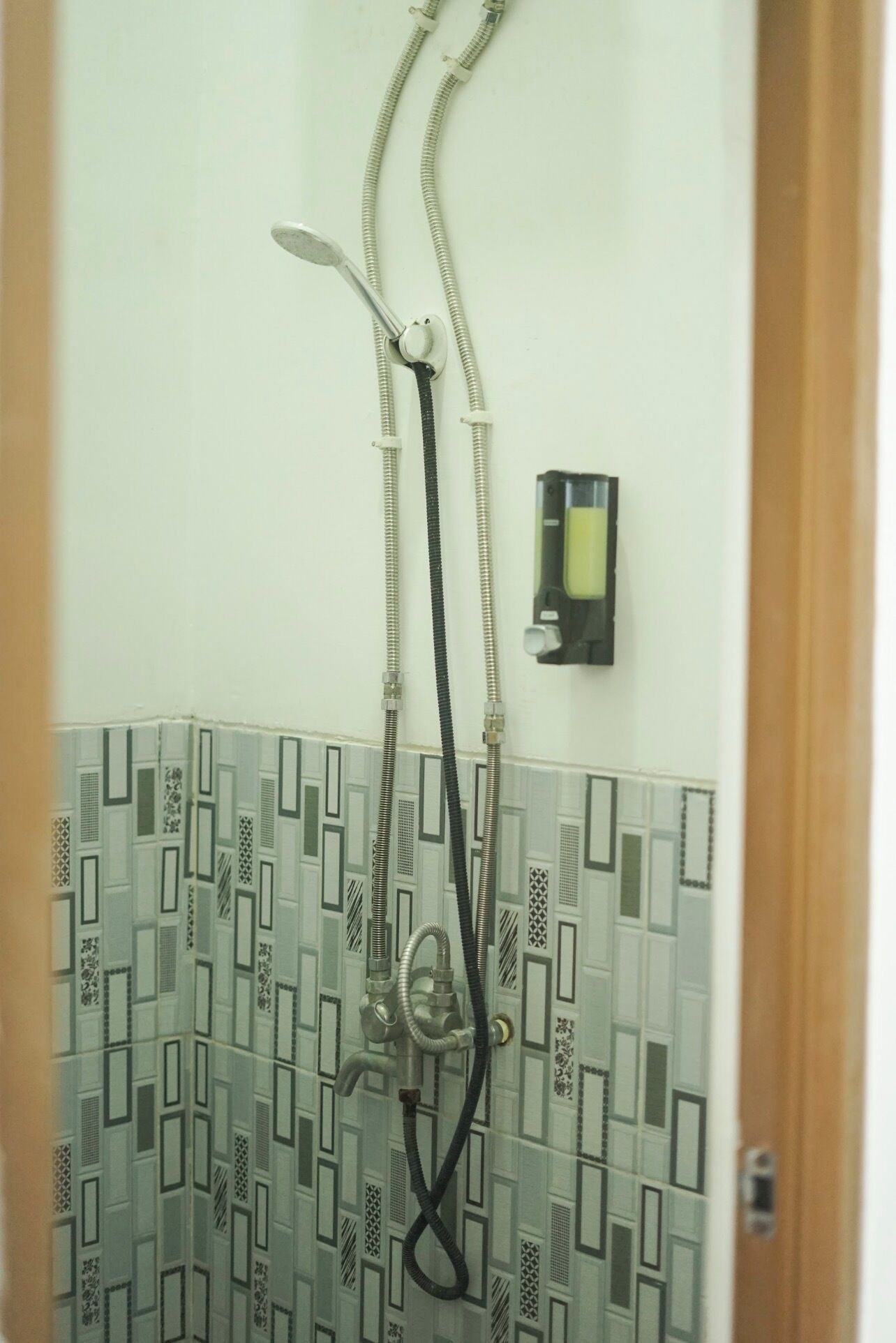 A shower with a control panel and a patterned tile wall.