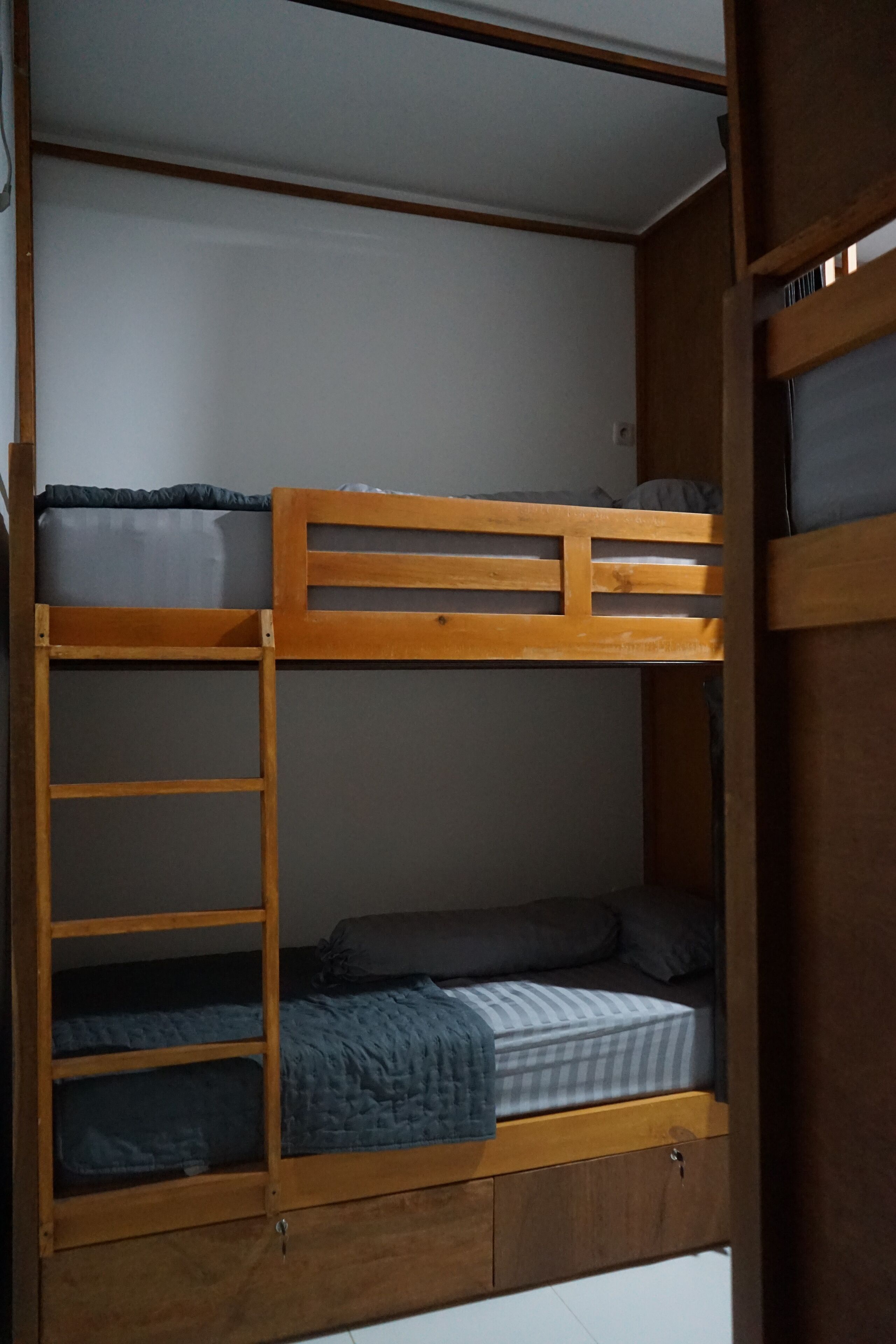 A bunk bed with a ladder, a lower bunk with a blanket, and a mattress with a pillow.