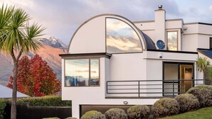 Una casa moderna de dos pisos con un amplio ventanal circular, una antena parabólica y un garaje.