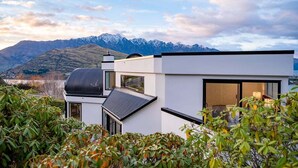Un edificio moderno con techo plano, ventanas amplias y vistas a montañas nevadas.