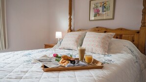 A neatly made bed with a floral quilt, a tray with croissants, a glass of orange juice, and a newspaper. - Mount Pleasant Farm, Dunwich (Dunwich)
