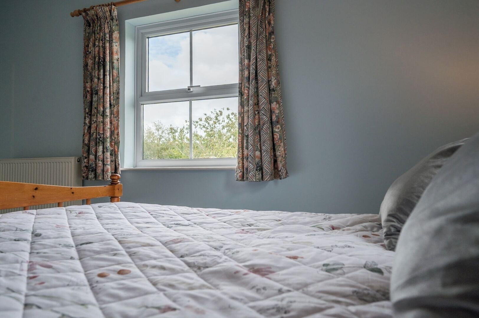 Ein Schlafzimmer mit Bett, Fenster und Vorhängen.