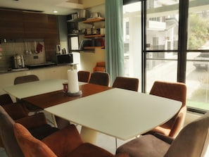 A modern kitchen with a dining area, a large window, and a view of the street.