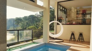 A modern indoor pool with a view of a forested hillside. - Charming 5-bedroom Villa in Baguio with Heated Dipping Pool :Glass & Green Perch (Baguio)