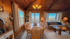 A wooden interior with a dining table surrounded by chairs, a sofa, and a coffee table. - Kohler Cottage - 4 BR Oceanfront Cottage in Southern Shores w/Elevator (Southern Shores)