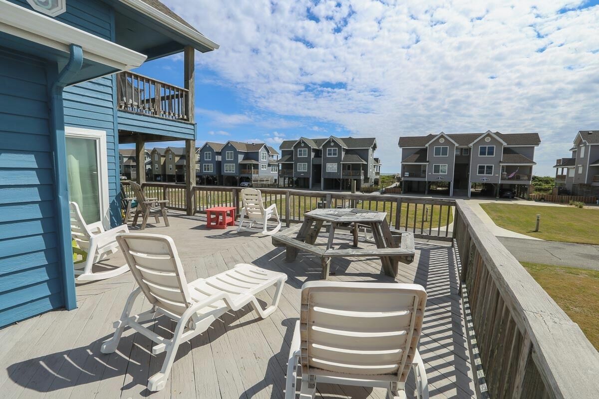 A deck with outdoor furniture, a wooden fence, and a view of multiple townhouses.