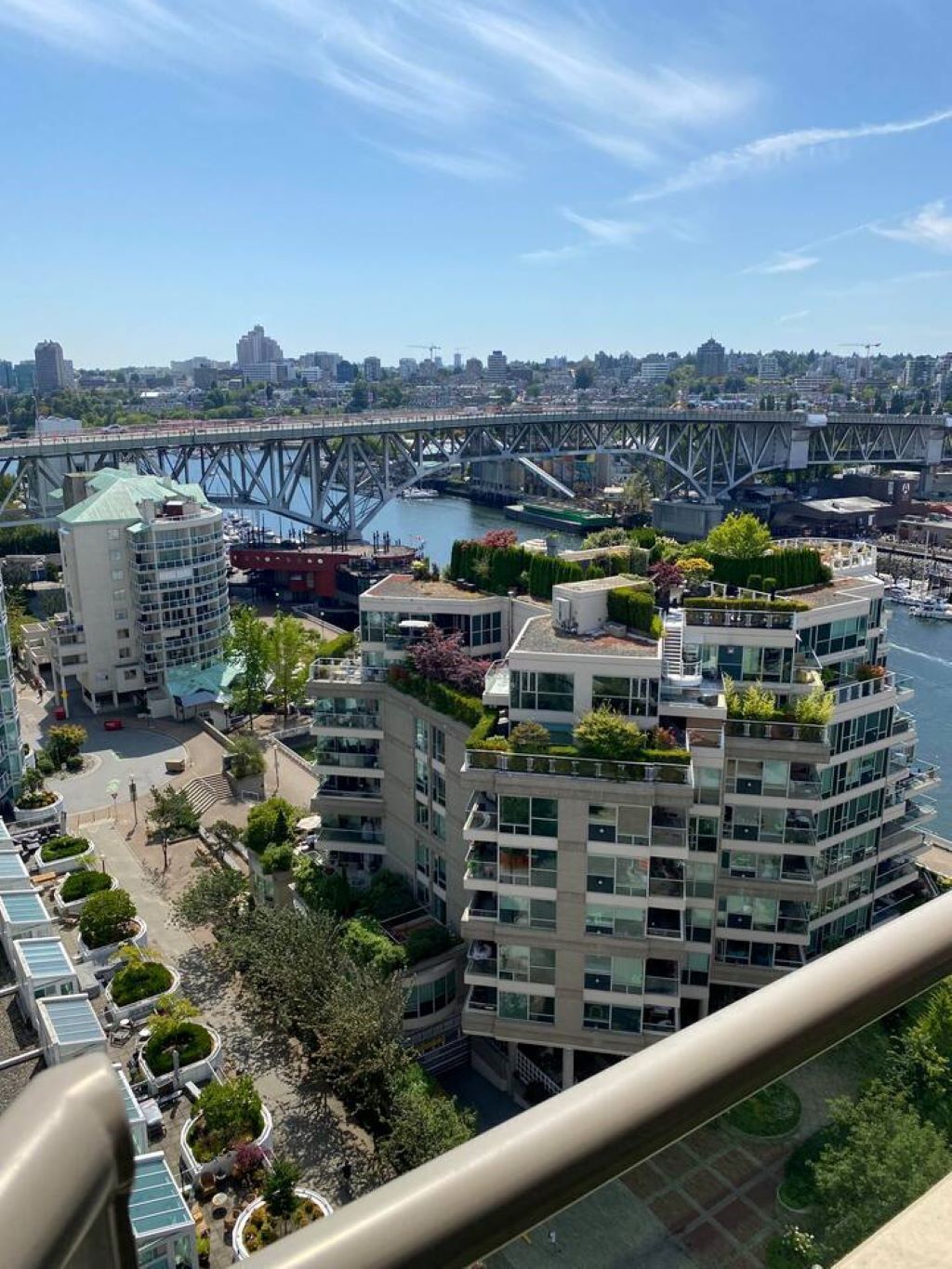 A high-rise building with multiple balconies, a river, and a bridge in the background.