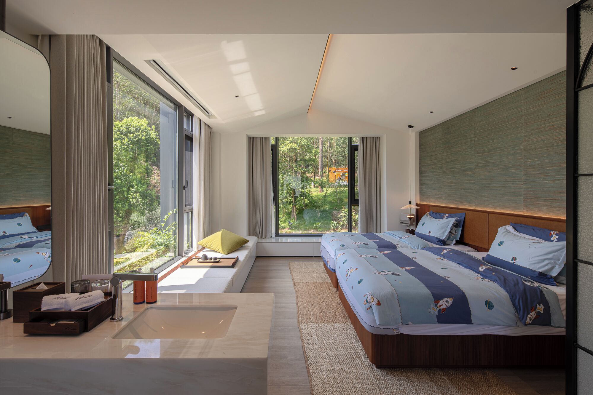 A modern bedroom with a large bed, a sofa, and a view of the outdoors.