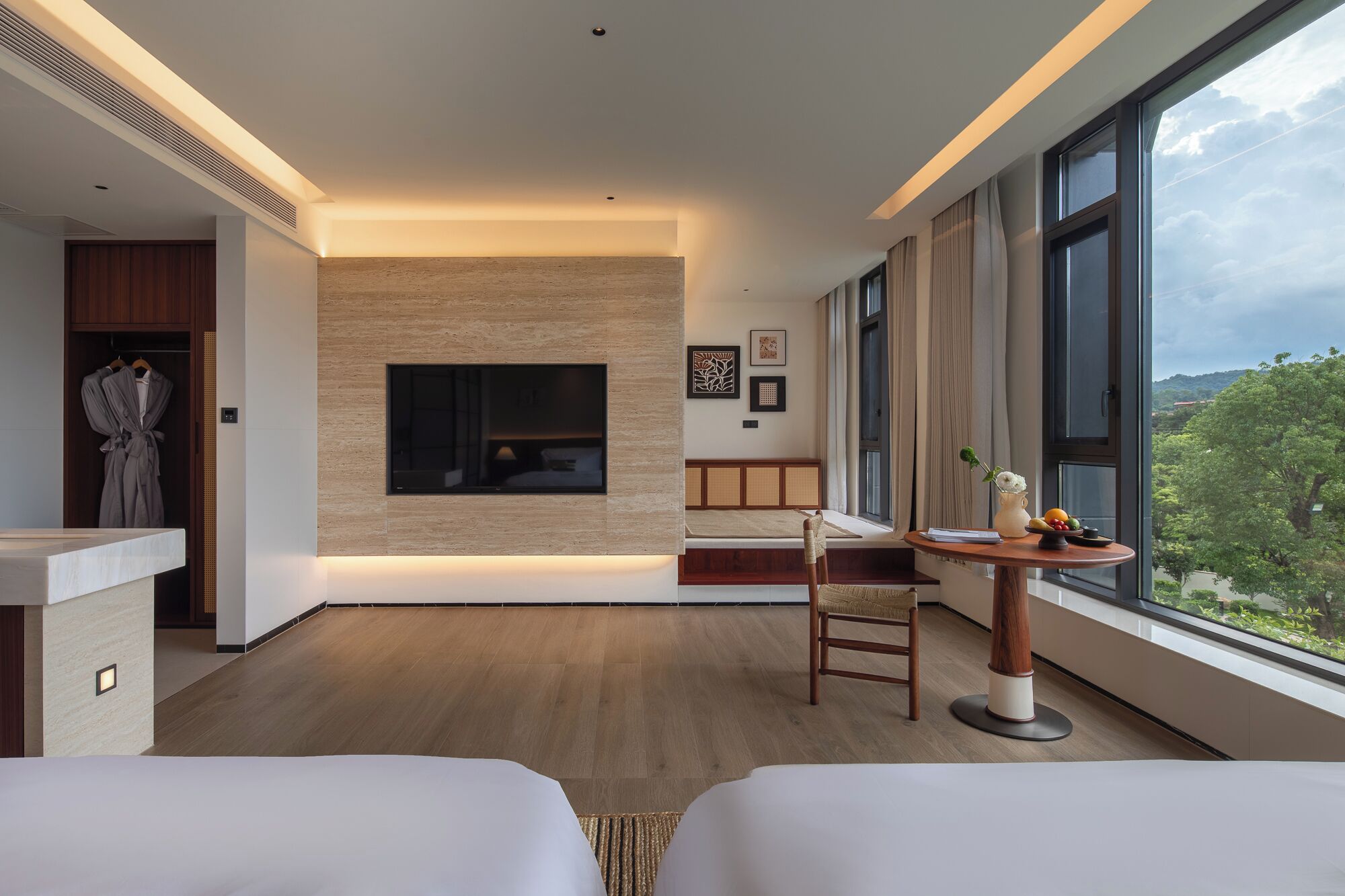 Une chambre d’hôtel moderne dotée d’un grand lit, d’un petit bureau, d’un coin salon avec vue et d’une cheminée.