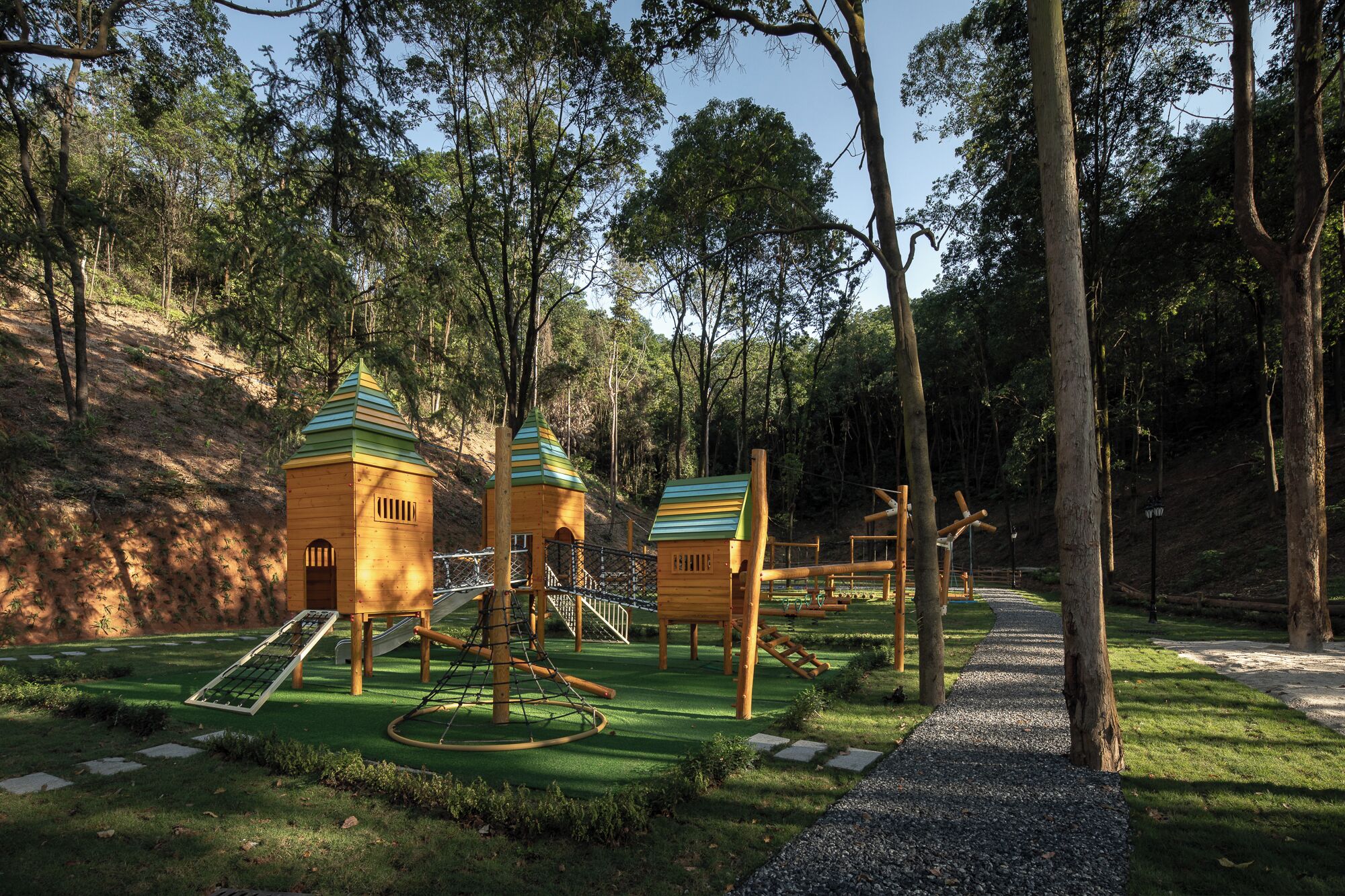 A playground with climbing structures, slides, and a rope bridge.