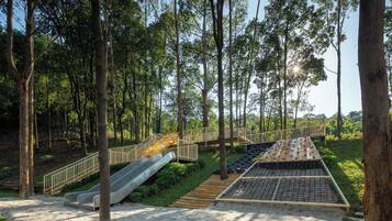 A playground with a slide, a small bridge, and a tire track area.