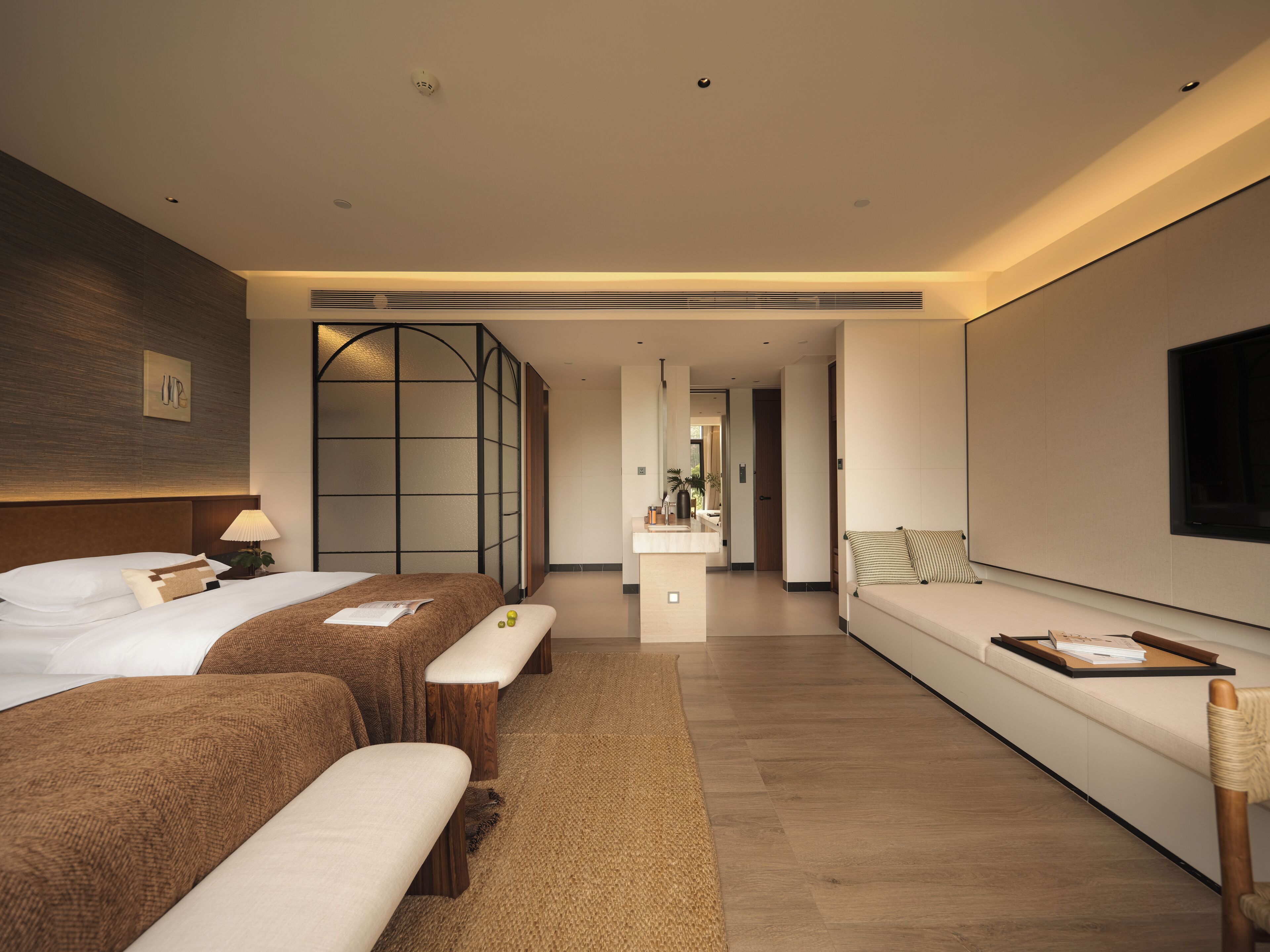 A modern hotel room with a large bed, a sofa, a desk, and a TV.