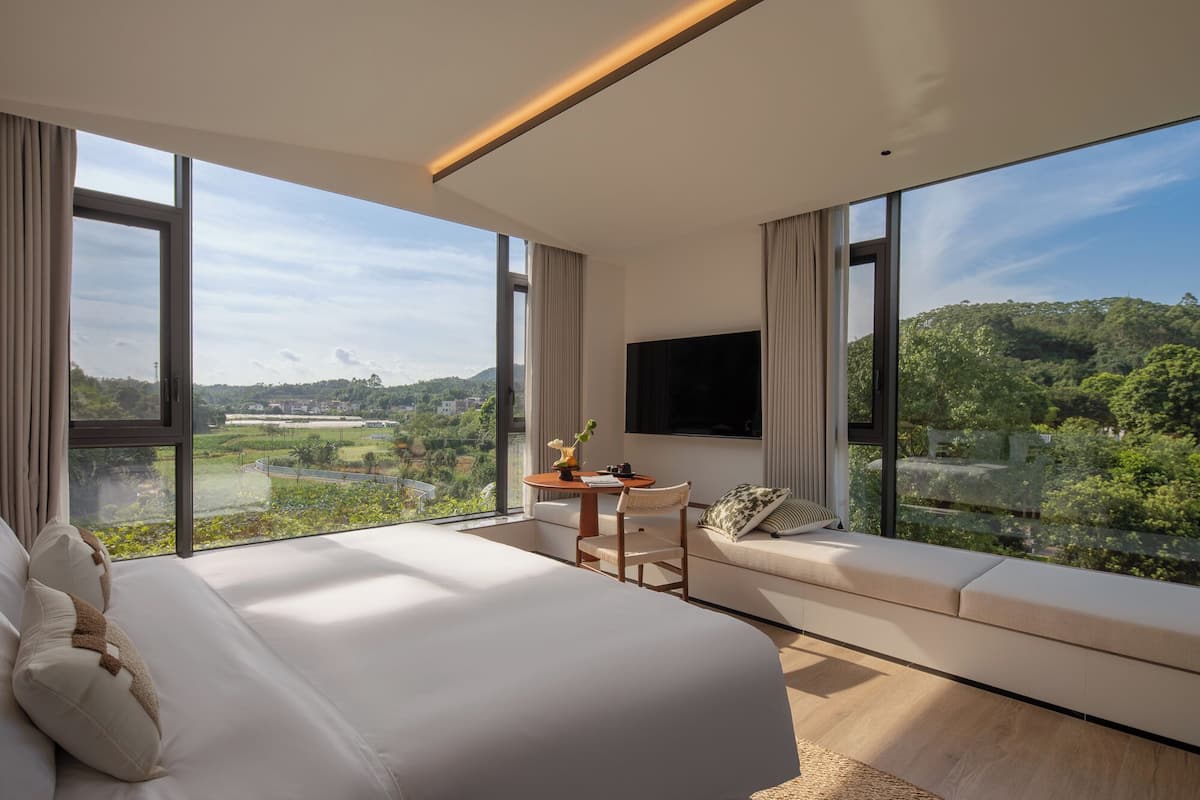 Een moderne slaapkamer met een groot bed, een zithoek en een televisie.